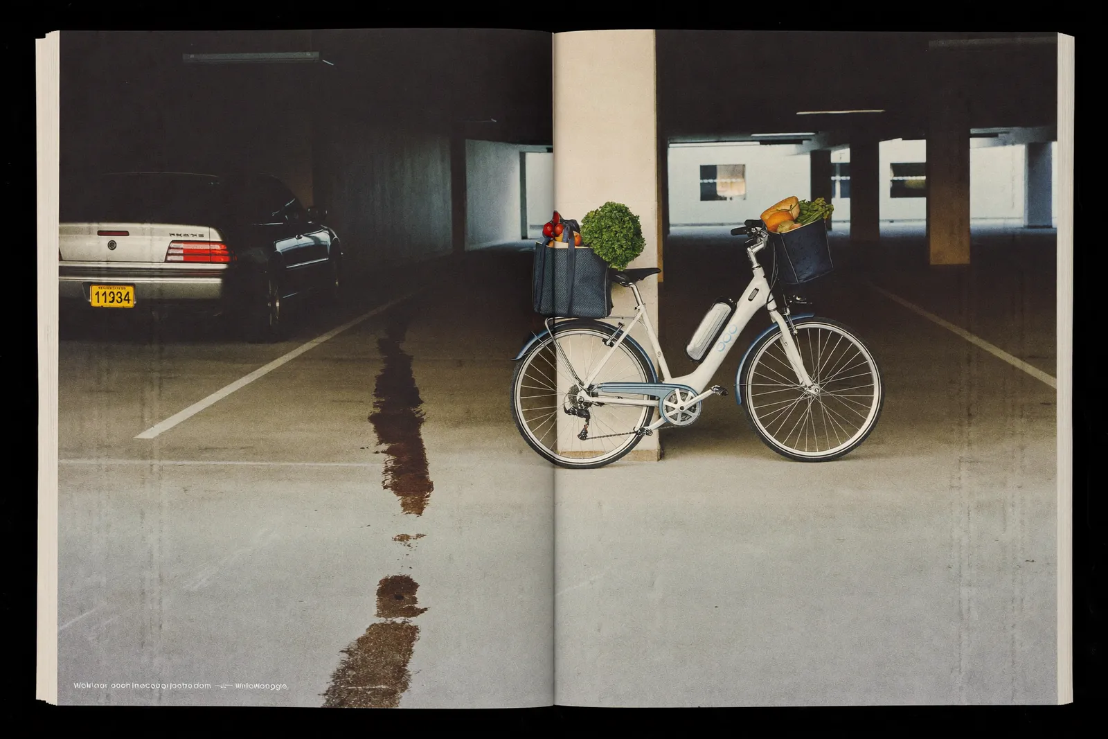 An e-bike with loaded grocery panniers parked in an empty garage bay, oil stain on the concrete