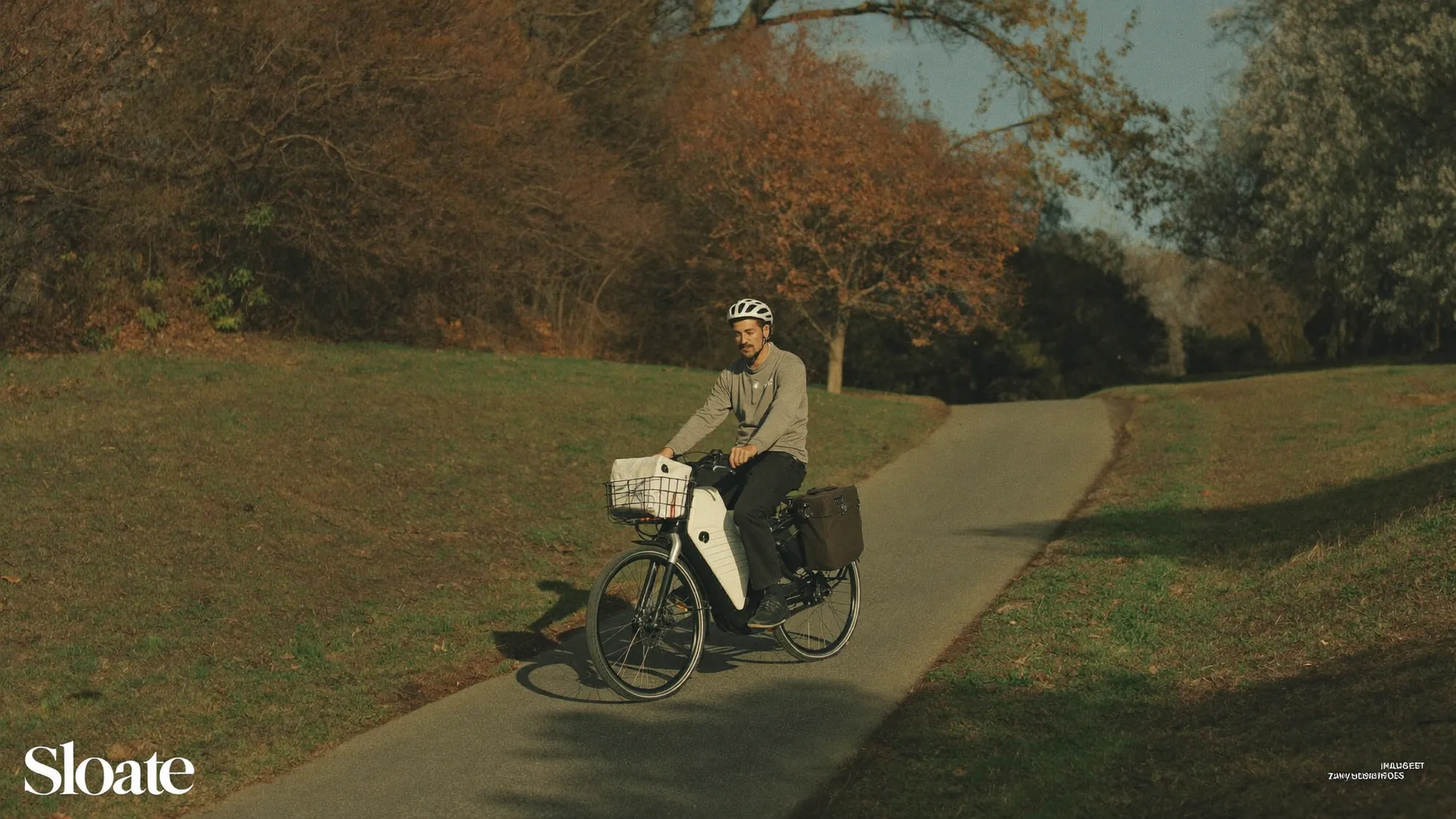 A relaxed man riding an e-bike up a suburban hill at golden hour, upright, panniers loaded